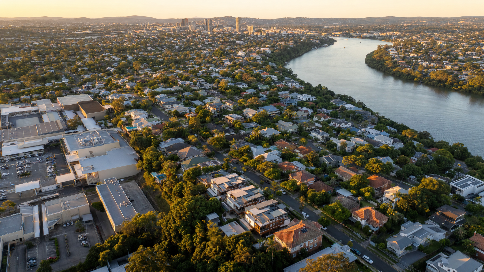 Aerial view of Indooroopilly, Brisbane, with the Brisbane River curving past, mix of mid-century and modern homes, and the suburb's shopping centre visible