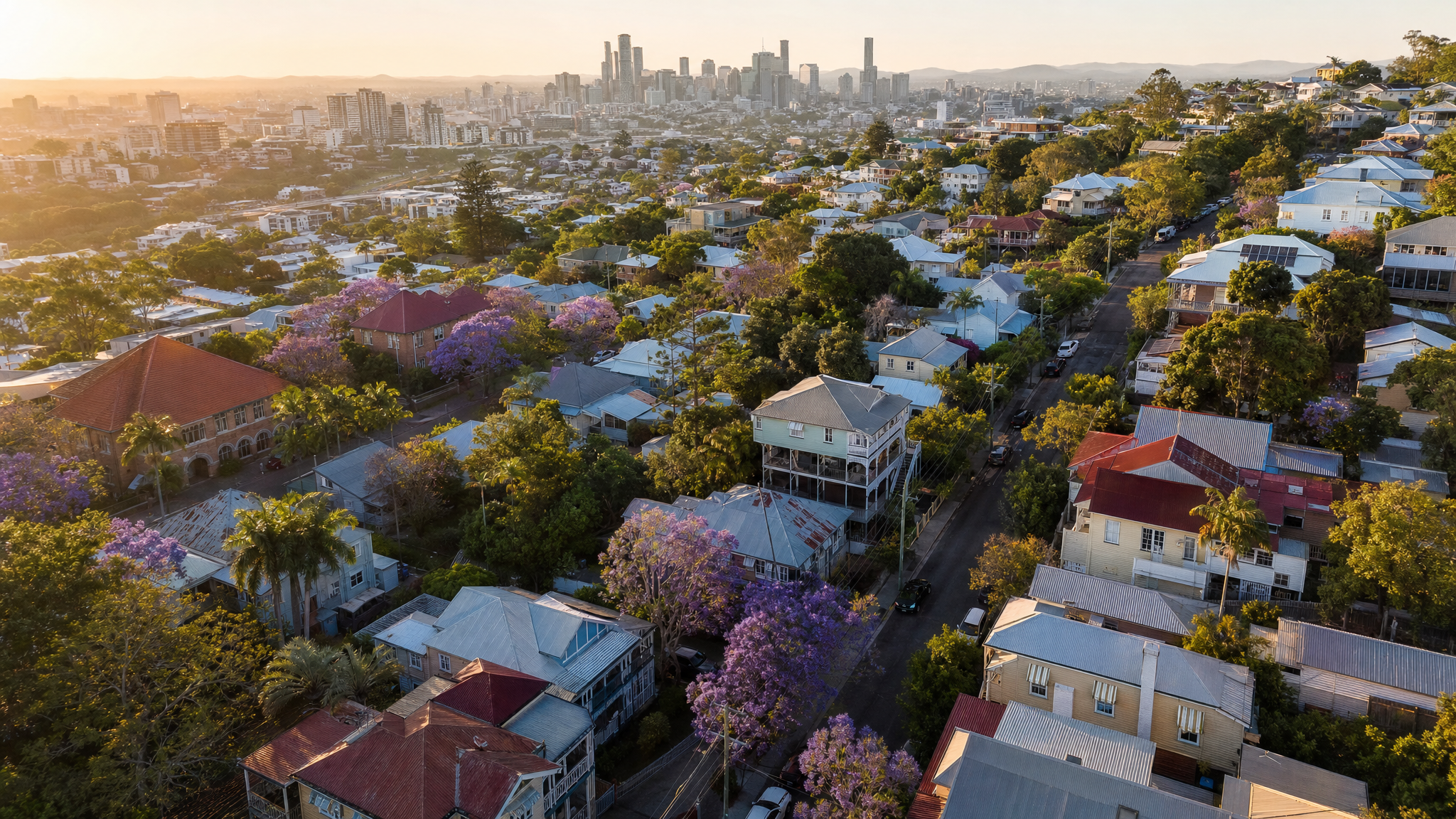 Aerial view of Paddington, Brisbane, with packed Queenslander homes climbing hilly streets and jacaranda trees in bloom